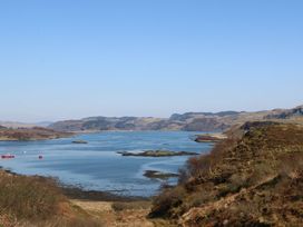 A coastal landscape with a body of water surrounded by hills and scattered small boats at Sula in Cullipool Isle Of Luing