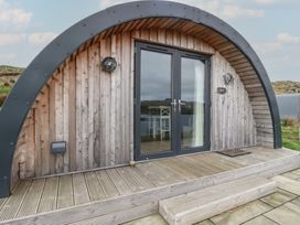 A wooden curved front entrance with glass double doors and steps at Sula in Cullipool Isle Of Luing