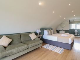 A bedroom with a green sofa a bed with pillows folded towels and a small sink at Sula in Cullipool Isle Of Luing