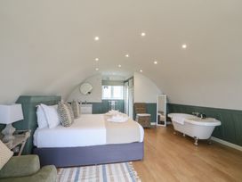 A bedroom with a bed a chair a bathtub and a mirror at Sula in Cullipool Isle Of Luing