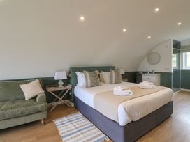 A bedroom with a double bed two bedside tables lamps a green sofa and a sink area at Sula in Cullipool Isle Of Luing