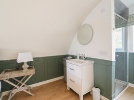 A bathroom with a white sink cabinet a round mirror a wooden tray table with a lamp and a glass shower enclosure at Sula Cullipool Isle Of Luing