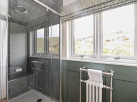 A bathroom with a glass shower enclosure a window with patterned blinds and a wall-mounted towel radiator at Sula in Cullipool Isle Of Luing
