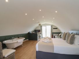 A bedroom with a bed pillows towels a bathtub a sofa and a kitchenette at Sula Cullipool Isle Of Luing