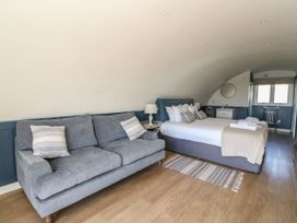 A bedroom with a gray sofa, bed with pillows and folded towels, a small side table with lamp and a window at Scarba Cullipool Isle Of Luing