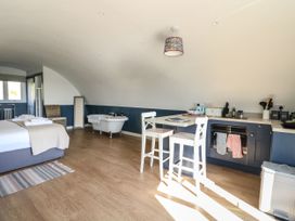 A room with a bed white chairs kitchenette and a bathtub at Scarba in Cullipool Isle Of Luing