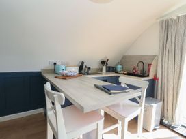 A small kitchen area with a breakfast bar two white chairs and kitchen appliances at Scarba in Cullipool Isle Of Luing