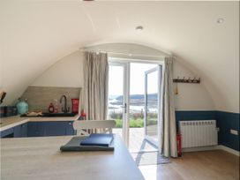 A kitchen with a counter a chair and a glass door leading outside at Scarba in Cullipool Isle Of Luing