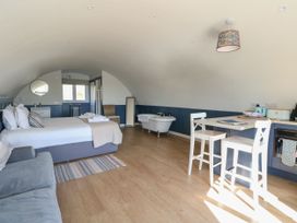 A studio room with a bed sofa bathtub dining table and kitchen area at Scarba in Cullipool Isle Of Luing