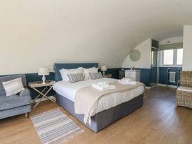 A bedroom with a bed a sofa two lamps a rug and a shower at Scarba in Cullipool Isle Of Luing