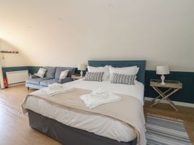 A bedroom with a bed with pillows and folded towels a blue sofa two bedside tables with lamps and a rug on the floor at Scarba in Cullipool Isle Of Luing