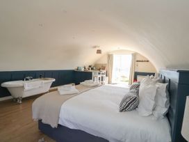 A bedroom with a bed towels bathtub and kitchenette at Scarba in Cullipool Isle Of Luing