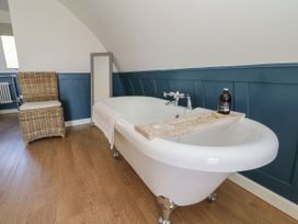 A bathroom with a white clawfoot bathtub a wicker chair and a floor mirror at Scarba in Cullipool Isle Of Luing