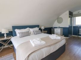 A bedroom with a large bed with towels on it bedside tables with lamps a sink a mirror a shower and a window at Scarba in Cullipool Isle Of Luing