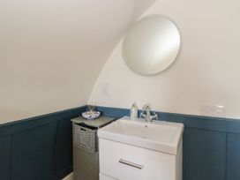 A bathroom sink with a round mirror above and a small cabinet with a basket next to it at Scarba Cullipool Isle Of Luing