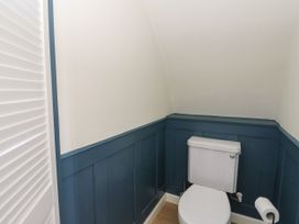 A small bathroom with a white toilet blue paneled walls and a white louvered door at Scarba in Cullipool Isle Of Luing