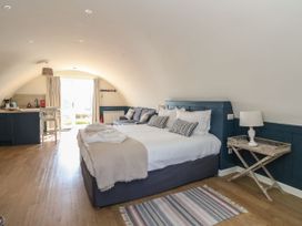A bedroom with a king size bed a sofa small kitchen and a door leading outside at Scarba in Cullipool Isle Of Luing