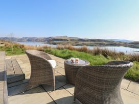 A patio with wicker chairs and table overlooking water and hills at Scarba in Cullipool Isle Of Luing