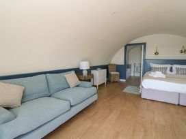 A bedroom with a blue sofa white nightstand bed and wooden floor at Torsa Cullipool Isle Of Luing