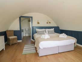 A bedroom with a double bed with folded towels two wall lamps wicker chair and wooden floor at Torsa Cullipool Isle Of Luing