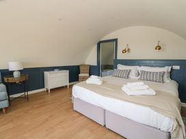 A bedroom with a large bed with towels bedside tables lamp dresser and wicker chair at Torsa Cullipool Isle Of Luing