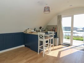 A kitchen corner with blue cabinets a small countertop table with two white chairs and glass doors overlooking a water view at Torsa in Cullipool Isle Of Luing