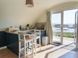A kitchen with bar stools countertop toaster and sink next to glass doors overlooking water at Torsa in Cullipool Isle Of Luing