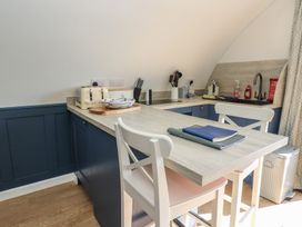 A kitchen with a countertop, white chairs, toaster, knife set, utensils, sink, and countertop appliances at Torsa Cullipool Isle Of Luing
