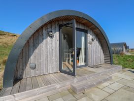 A wooden curved cabin with glass door open and steps leading to a paved patio at Torsa in Cullipool Isle Of Luing
