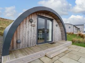 A wooden cabin with curved roof and glass double doors on a stone and wooden deck at Fladda in Cullipool Isle Of Luing