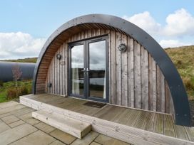 A wooden arched cabin with double glass doors and a small step outside at Fladda in Cullipool Isle Of Luing