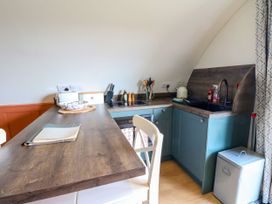 A kitchen area with a wooden counter white chair sink stove and kitchen utensils at Fladda Cullipool Isle Of Luing
