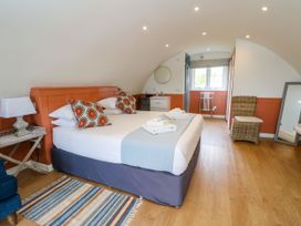 A bedroom with a double bed bedside table and lamp a chair a mirror and a window at Fladda in Cullipool Isle Of Luing