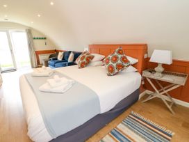 A bedroom with a bed with colorful pillows towels a blue couch a side table with a lamp and a patterned rug at Fladda in Cullipool Isle Of Luing