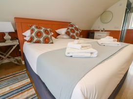 A bedroom with a bed and patterned pillows next to a bedside table with a lamp and a sink with a mirror at Fladda Cullipool Isle Of Luing