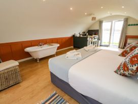 A bedroom with a bed towels a freestanding bathtub and a small kitchen area with a table and chairs at Fladda in Cullipool Isle Of Luing