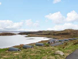 A group of small cabins near a body of water and grassy hills at Fladda in Cullipool Isle Of Luing