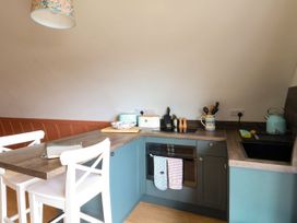 A kitchen with blue cabinetry a black oven stove and sink with white chairs at Losal Cullipool Isle Of Luing