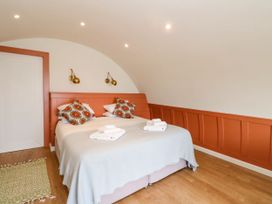 A bedroom with two beds pushed together white bedding patterned pillows and folded towels on a wooden floor at Losal Cullipool Isle Of Luing