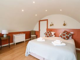 A bedroom with a double bed two patterned pillows white towels wicker chair white dresser and side table with lamp at Losal Cullipool Isle Of Luing