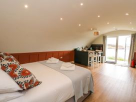 A bedroom with a bed and towels a kitchenette with two chairs and glass doors overlooking a landscape at Losal Cullipool Isle Of Luing