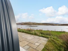 A view of a river with grass and a stone patio at Losal Cullipool Isle Of Luing