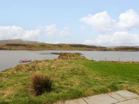 A grassy yard with a small boat on water and hills in the background at Losal Cullipool Isle Of Luing