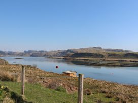 A lakeside view with a wooden shed near the water and hills in the background at Losal Cullipool Isle Of Luing