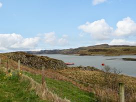 A coastal landscape with a boat on the water and a fence in the foreground at Losal Cullipool Isle Of Luing