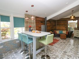 A kitchen with a bar stools and a table at Lilac Cottage in Grange-Over-Sands