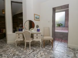 A vanity with a chair and a bathtub at Lilac Cottage in Grange-Over-Sands