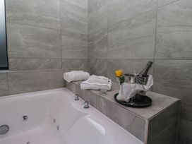 A bathroom with bathtub, towels, champagne and a flower at Lilac Cottage in Grange-Over-Sands
