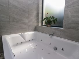 A bathroom with a bathtub and a plant at Lilac Cottage in Grange-Over-Sands