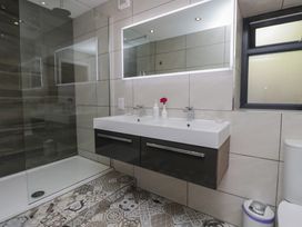A bathroom with a sink, toilet, shower, and mirror at Lilac Cottage in Grange-Over-Sands